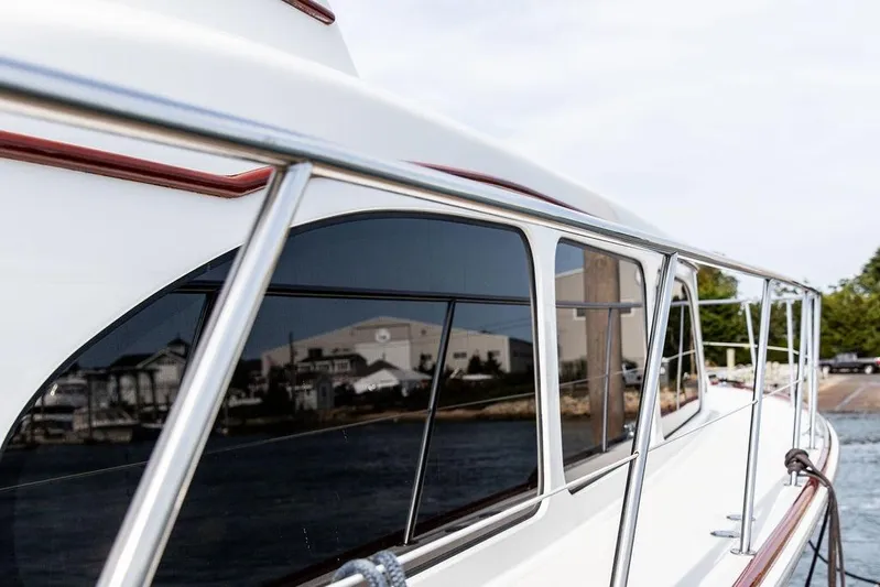 Marina Yacht Photos Pics 2008 Huckins Linwood yacht with sleek design and reflective windows docked by the shore.