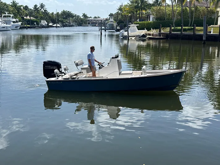  Yacht Photos Pics 2024 Dragonfly 21 Spanish Wells boat on a calm waterway, surrounded by palm trees.