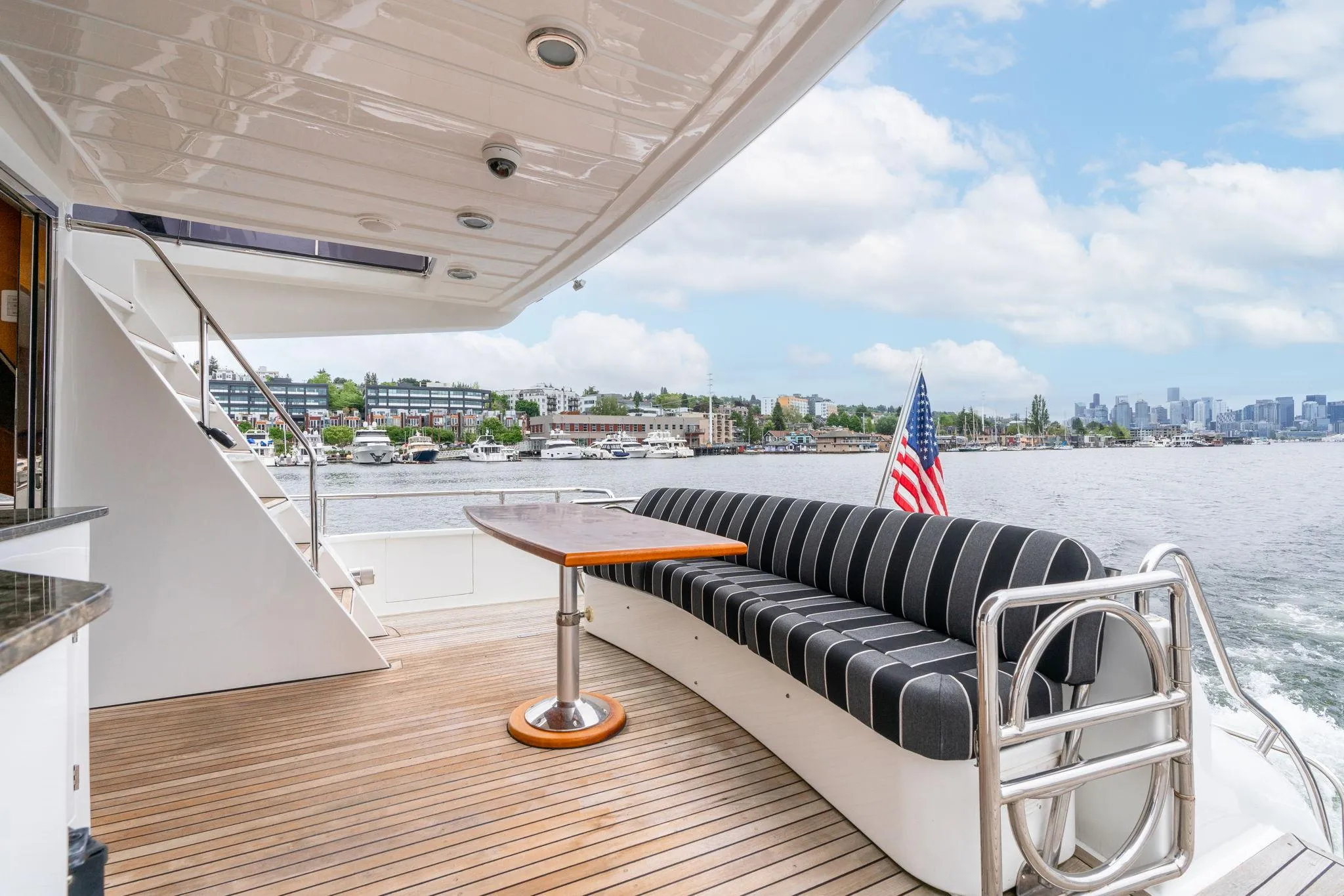 Luxurious 1999 Vitech 68' Pilothouse yacht deck with seating, table, and scenic waterfront view.