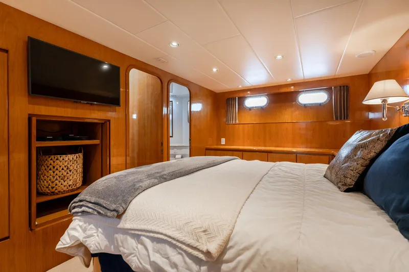 Royal Viking Yacht Photos Pics Luxurious bedroom in 1999 Vitech 68' Pilothouse yacht with cozy bedding and elegant wood paneling.