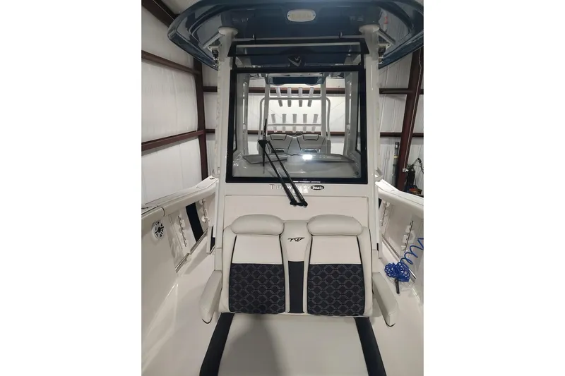  Yacht Photos Pics 2023 Tidewater 292 CC Adventure boat interior with seating and console in a storage facility.