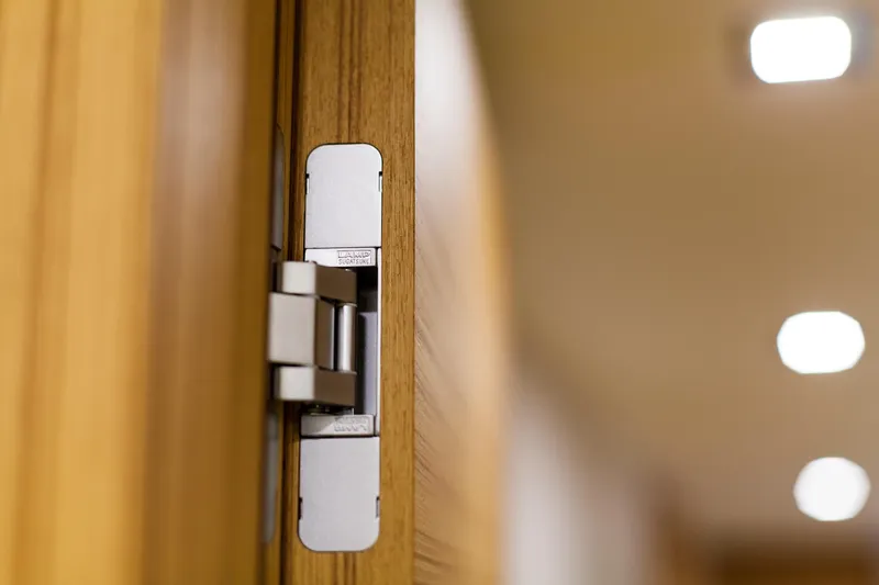 Yacht Photos Pics Close-up of a modern door hinge on a wooden door, indoors.