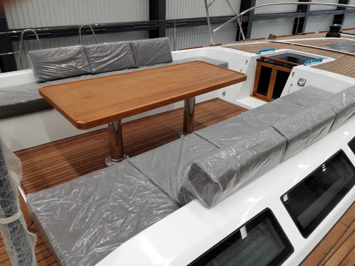  Yacht Photos Pics Luxurious deck seating on 2026 Mazarin 72 Cruiser/Racer, featuring a wooden table and cushioned benches.