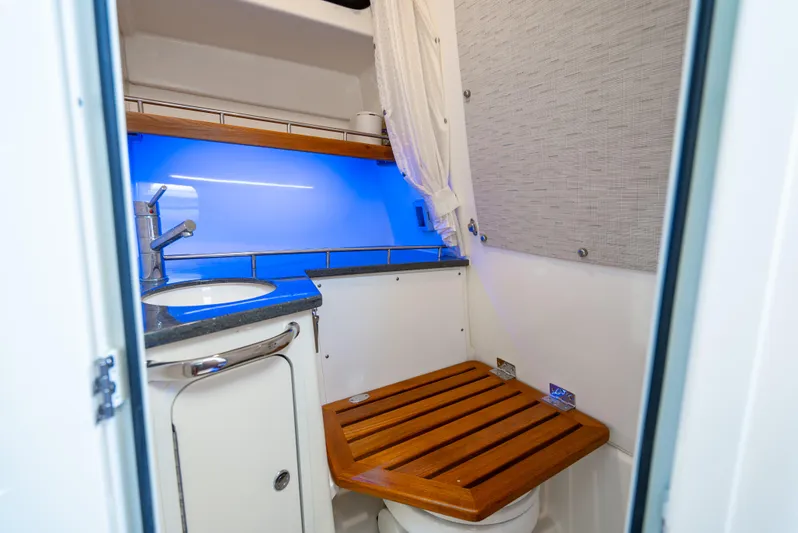  Yacht Photos Pics 2021 Boston Whaler 350 Realm bathroom with wooden seat, sink, and blue lighting.