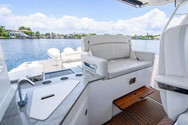  Yacht Photos Pics 2021 Boston Whaler 350 Realm interior with seating and kitchenette, overlooking serene waterfront.