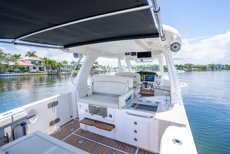  Yacht Photos Pics 2021 Boston Whaler 350 Realm boat interior with seating and helm, docked on a sunny day.