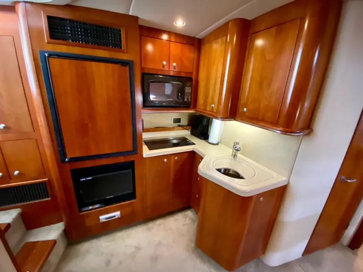  Yacht Photos Pics 2007 Cruisers Yachts 370 Express kitchen with wood cabinetry, microwave, and sink.
