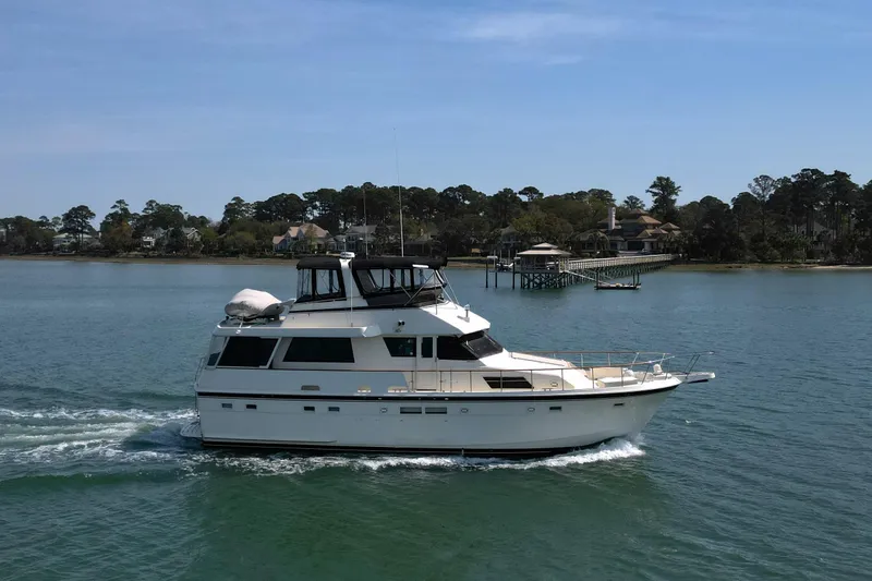 Lady Malan Yacht Photos Pics 1987 Hatteras 54 Motor Yacht cruising on a serene waterway near a coastal town.