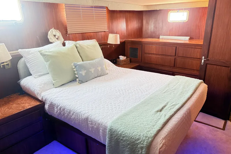 Lady Malan Yacht Photos Pics Luxurious bedroom interior of 1987 Hatteras 54 Motor Yacht with elegant wood paneling.
