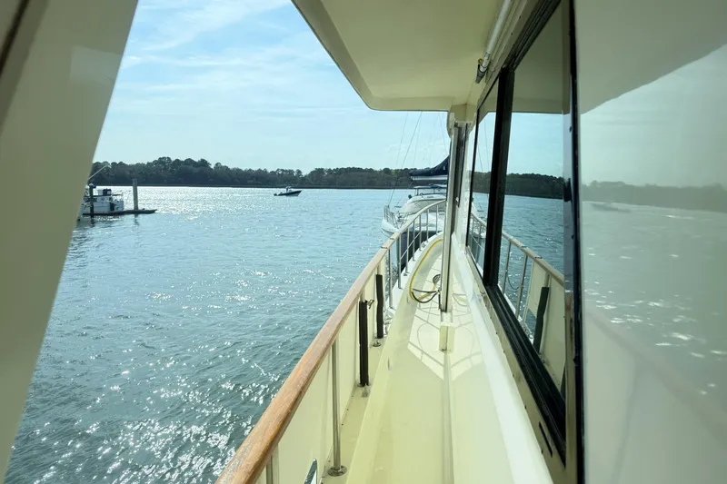 Lady Malan Yacht Photos Pics 1987 Hatteras 54 Motor Yacht cruising on a sunny day, reflecting on calm waters.