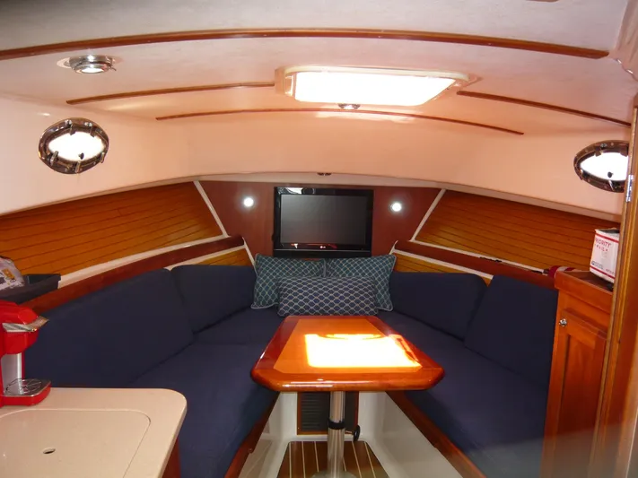 Last Hurrah Yacht Photos Pics 2008 Back Cove 29 interior with blue seating, wooden table, and TV. Cozy and elegant cabin design.