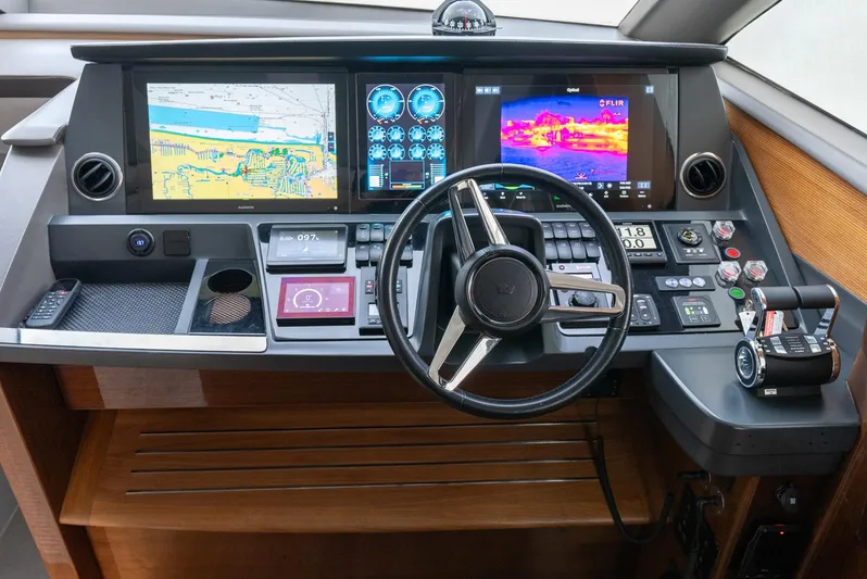 Fly By Yacht Photos Pics Control panel of 2019 Princess V65 yacht with navigation screens and steering wheel.