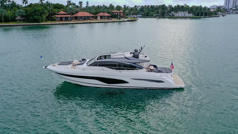 Fly By Yacht Photos Pics 2019 Princess V65 yacht cruising on serene waters near luxury waterfront homes.