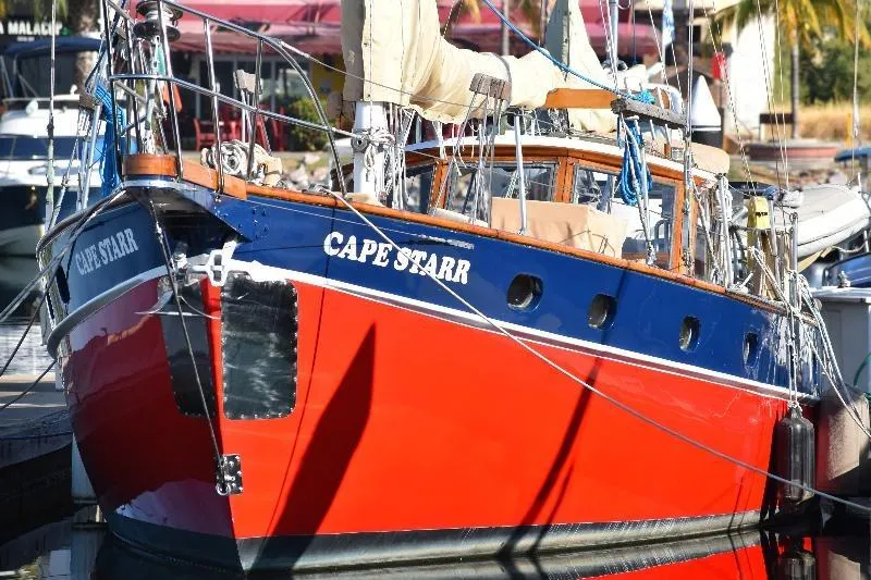 Red and blue 1958 Custom Steel Motorsailor "Cape Starr" docked at marina.