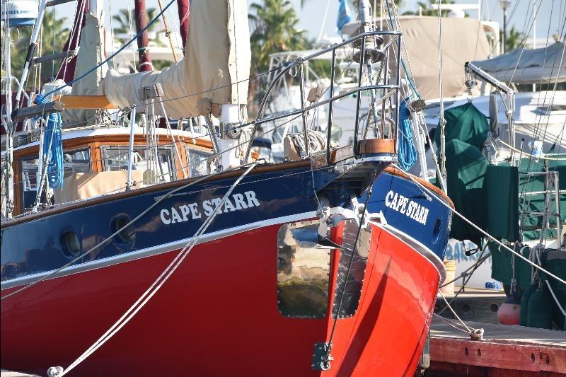 Custom 1958 Steel Motorsailor "Cape Starr" docked at marina, vibrant red and blue hull.