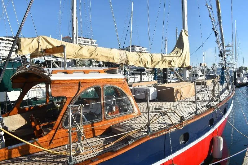 1958 Custom Steel Motorsailor with wooden cabin, docked in marina under clear blue sky.