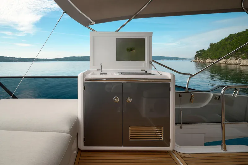  Yacht Photos Pics Luxurious 2023 Azimut 53 yacht deck with kitchenette, overlooking serene blue waters and lush coastline.