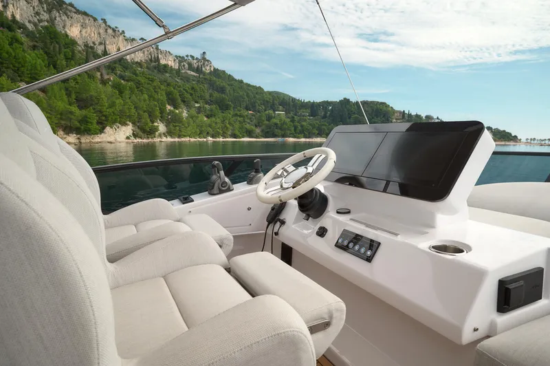  Yacht Photos Pics 2023 Azimut 53 yacht helm with modern controls, steering wheel, and scenic coastal backdrop.