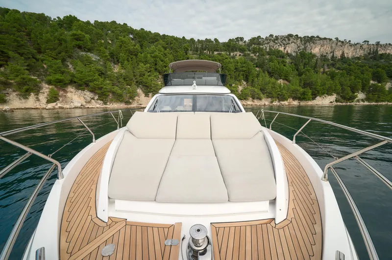  Yacht Photos Pics 2023 Azimut 53 yacht with sunbed, cruising near a forested coastline.