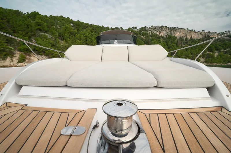  Yacht Photos Pics 2023 Azimut 53 yacht with cushioned deck, wooden flooring, and scenic background.