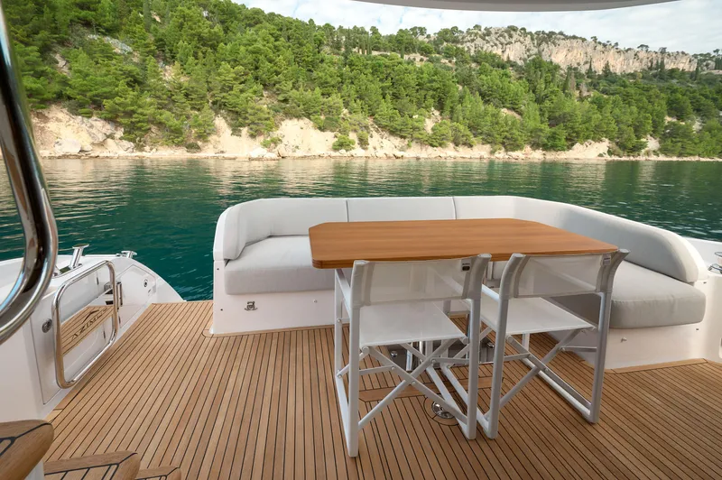  Yacht Photos Pics Luxury Azimut 53 yacht deck with seating and table, overlooking serene water and lush greenery.