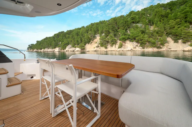  Yacht Photos Pics 2023 Azimut 53 yacht deck with seating, table, and scenic coastal view.