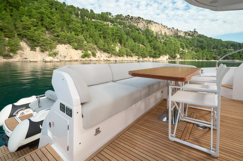  Yacht Photos Pics Luxury Azimut 53 yacht deck with seating, table, and scenic coastal view, 2023 model.