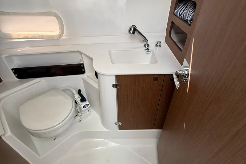  Yacht Photos Pics 2021 Beneteau Antares 9 bathroom with toilet, sink, and wooden cabinetry.