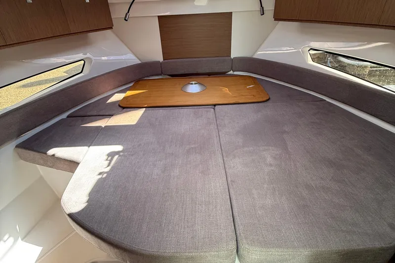  Yacht Photos Pics 2021 Beneteau Antares 9 interior with cozy seating and wooden table.