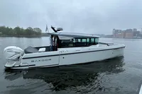 2022 Saxdor 320 GTC boat on a calm river with cityscape background.