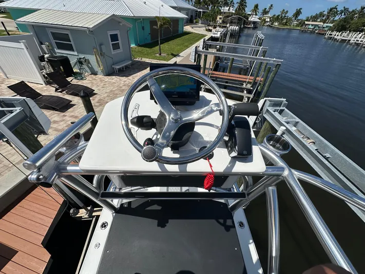 Yacht Photos Pics 2024 Lake & Bay 25 Open boat helm with steering wheel, docked by waterfront homes.