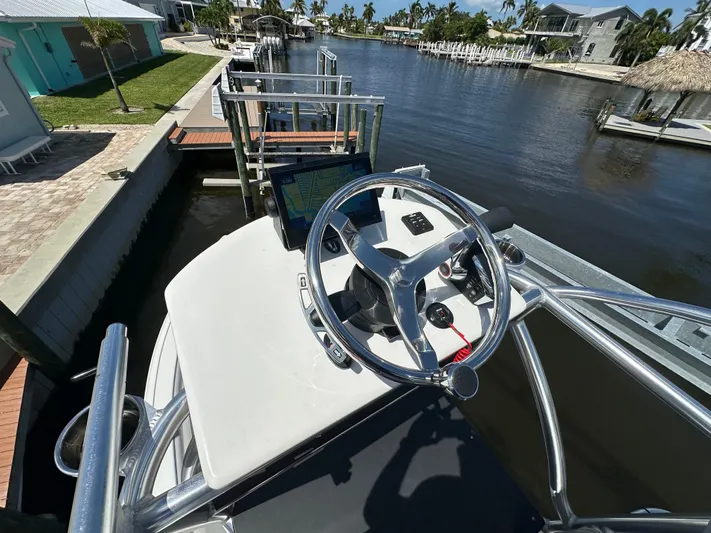  Yacht Photos Pics 2024 Lake & Bay 25 Open boat steering wheel and console at a dockside canal.