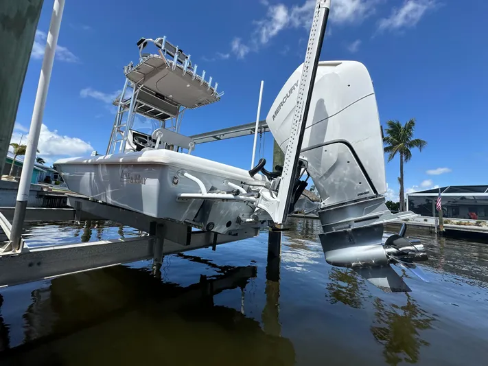  Yacht Photos Pics 2024 Lake & Bay 25 Open boat on lift, clear sky, palm trees in background.