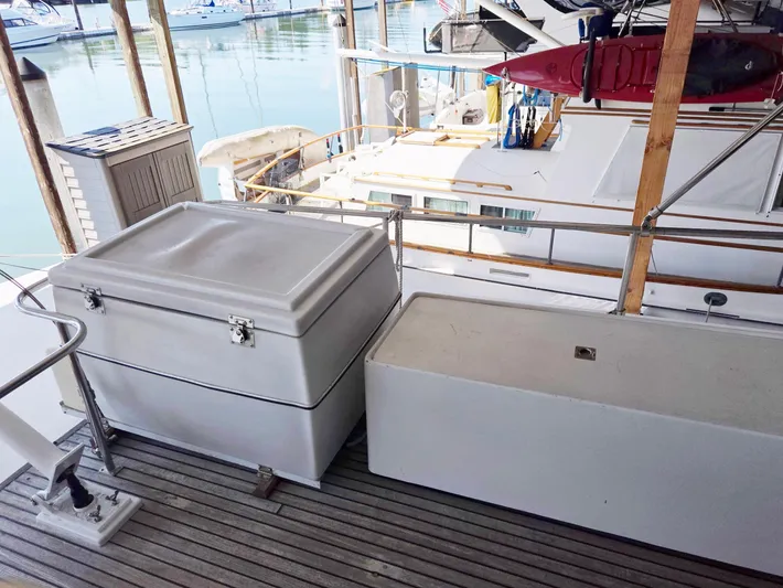 Carina Yacht Photos Pics Deck view of 1990 Grand Banks 36 Europa yacht with storage boxes and marina background.