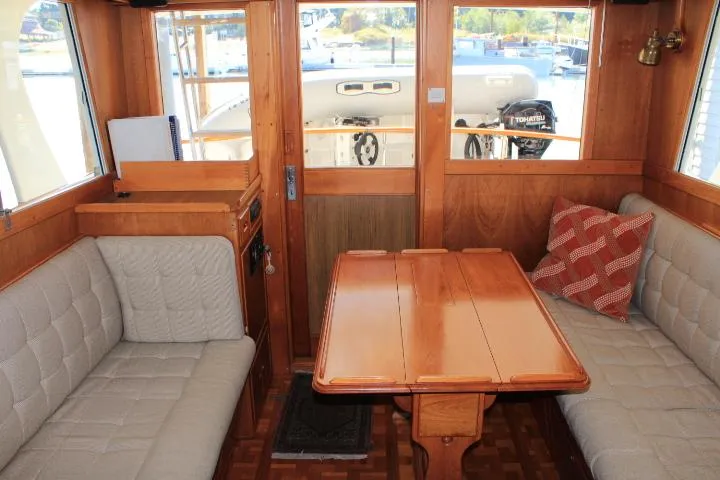 Carina Yacht Photos Pics Interior of 1990 Grand Banks 36 Europa yacht with wooden table and cushioned seating.