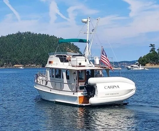 Carina Yacht Photos Pics 1990 Grand Banks 36 Europa yacht on serene water with lush green island backdrop.