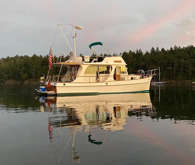 Carina Yacht Photos Pics 1990 Grand Banks 36 Europa yacht on calm water at sunset, reflecting trees and sky.