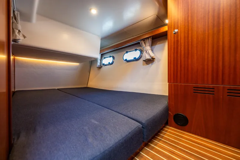 Yacht Photos Pics Cozy cabin interior of 2021 Nimbus 405 Coupé yacht with wooden accents and blue bedding.