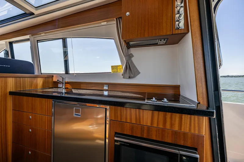  Yacht Photos Pics Luxurious kitchen interior of 2021 Nimbus 405 Coupé yacht with wood finish and modern appliances.