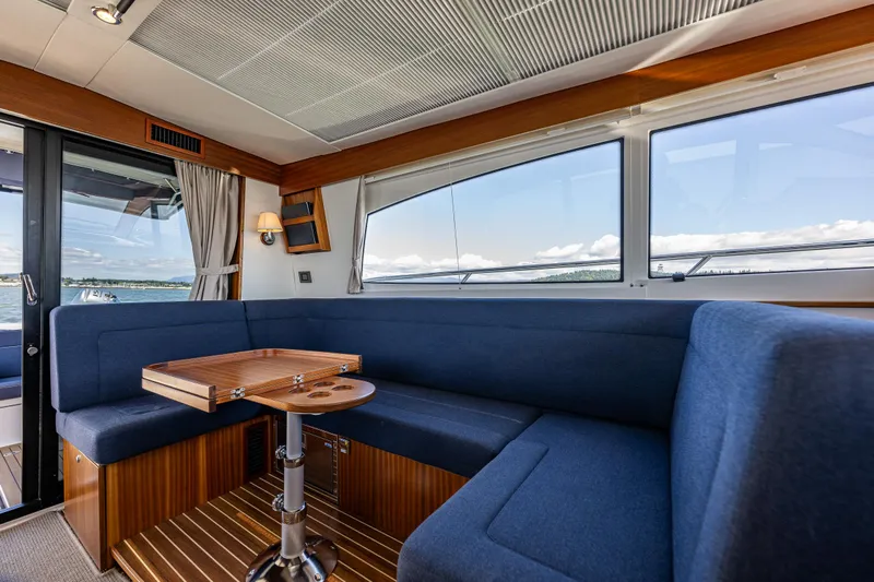 Yacht Photos Pics Luxurious interior of 2021 Nimbus 405 Coupé yacht with blue seating and wooden table.