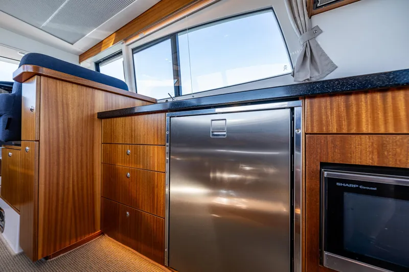  Yacht Photos Pics Luxurious interior of 2021 Nimbus 405 Coupé yacht with wood cabinetry and stainless steel appliances.
