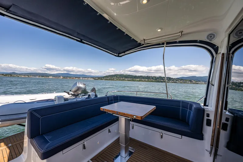  Yacht Photos Pics Luxurious seating area on 2021 Nimbus 405 Coupé yacht, overlooking serene waters and scenic landscape.