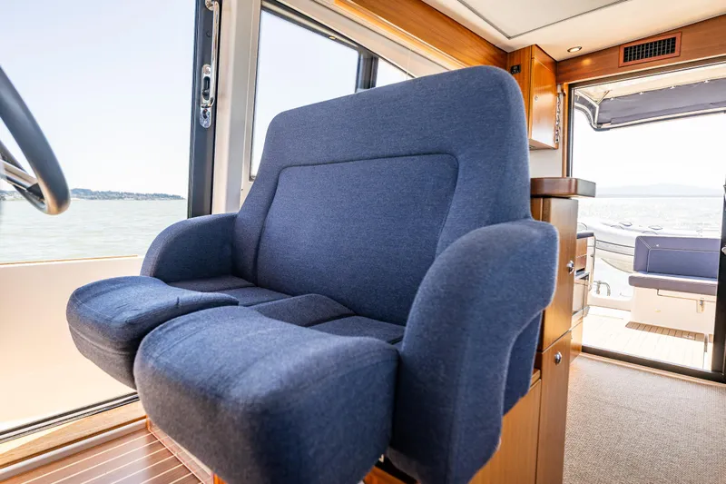  Yacht Photos Pics Blue captain's chair inside 2021 Nimbus 405 Coupé yacht, with scenic water view.