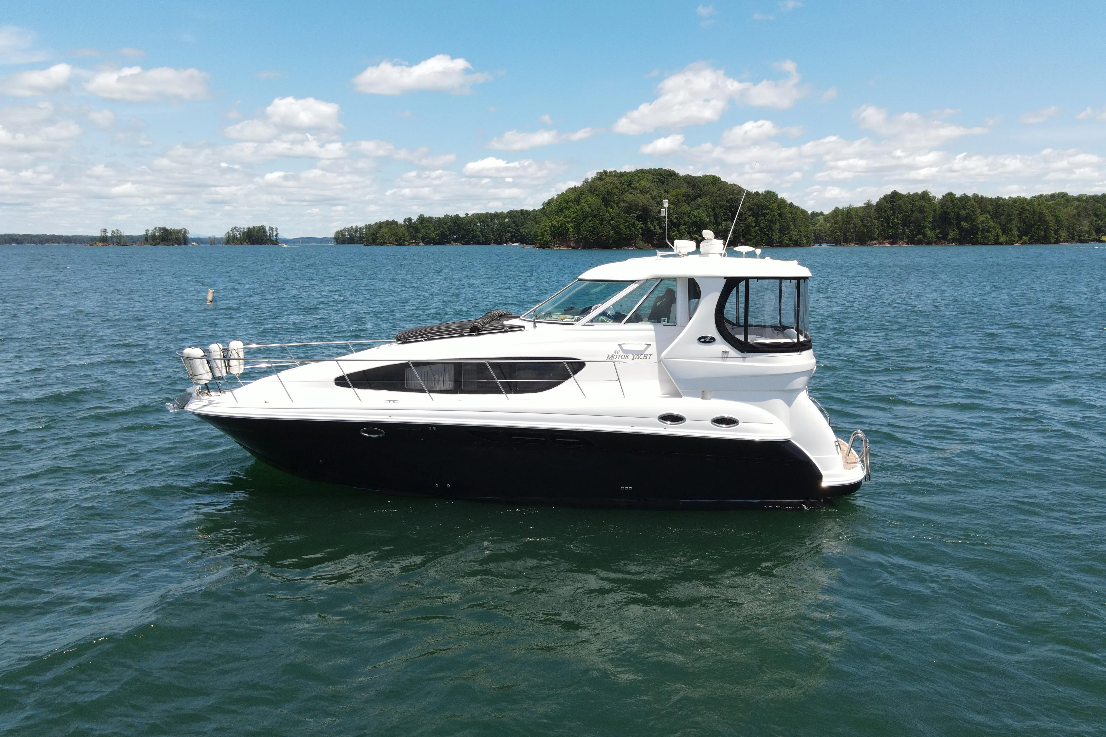  Yacht Photos Pics 2007 Sea Ray 40 Motor Yacht cruising on a serene lake under a clear blue sky.