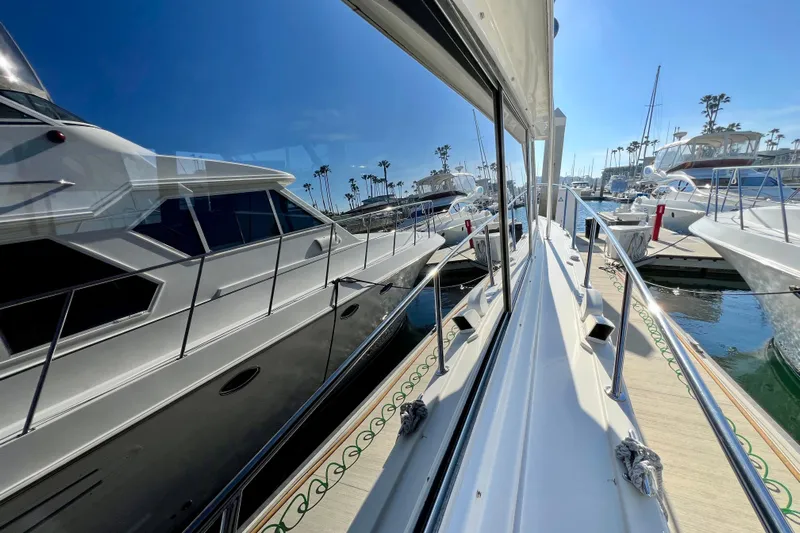 Live Wire Yacht Photos Pics 1982 Bertram 46 Convertible yacht docked in a sunny marina, reflecting on calm water.