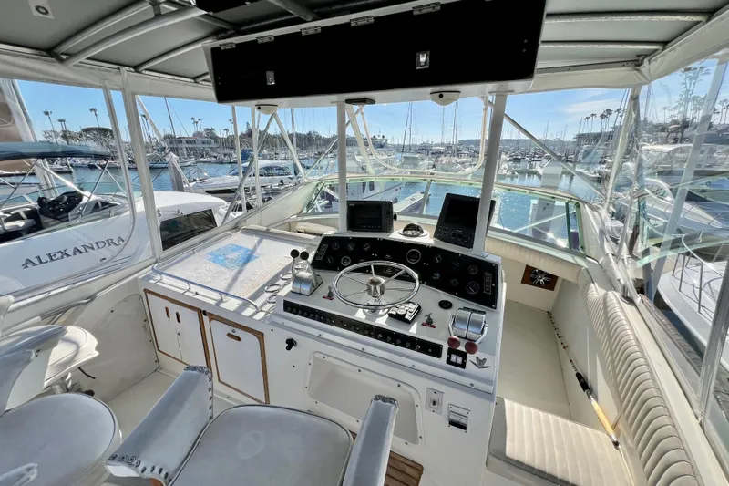 Live Wire Yacht Photos Pics 1982 Bertram 46 Convertible yacht cockpit with steering wheel, controls, and marina view.
