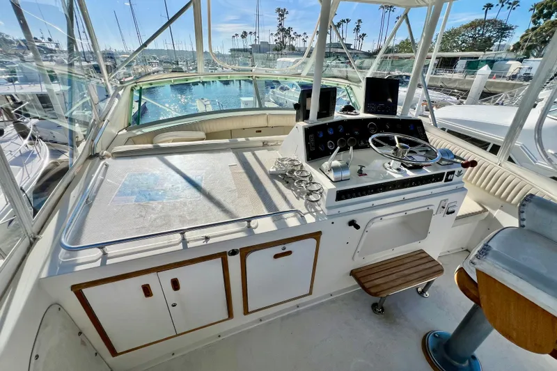 Live Wire Yacht Photos Pics 1982 Bertram 46 Convertible yacht helm with steering wheel, controls, and marina view.
