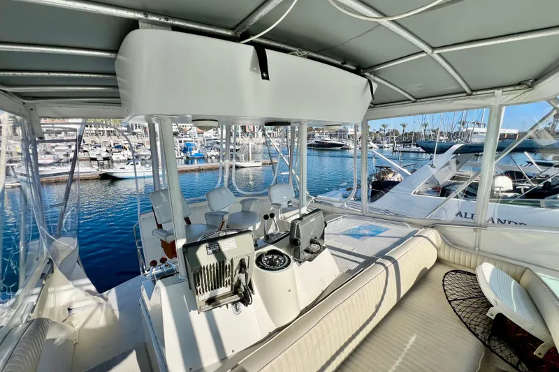 Live Wire Yacht Photos Pics 1982 Bertram 46 Convertible yacht interior with marina view, featuring helm and seating area.