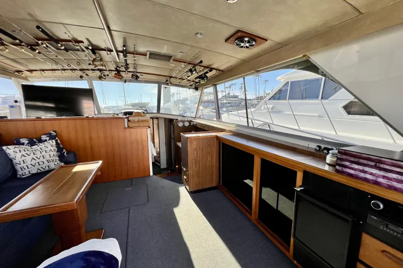 Live Wire Yacht Photos Pics Interior of 1982 Bertram 46 Convertible yacht with fishing rods and cozy seating area.
