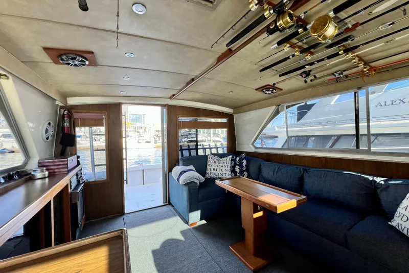 Live Wire Yacht Photos Pics Interior of 1982 Bertram 46 Convertible yacht with fishing rods and cozy seating area.